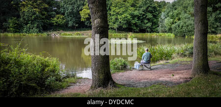 Ein Angler Angeln im alten Saal Teich in Thorndon Country Park in Essex. Stockfoto