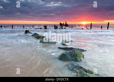 Happisburgh Strand und die verfallenen Küstenschutzes bei Sonnenaufgang an der Küste von Norfolk. Stockfoto