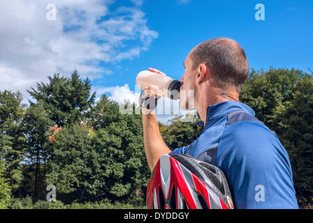 Männliche Radfahrer trinken aus einer Flasche Wasser. Stockfoto