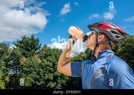 Männliche Radfahrer trinken aus einer Flasche Wasser. Stockfoto