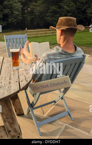 Ein Mann mit einem Buch und Glas Bier entspannen. Stockfoto