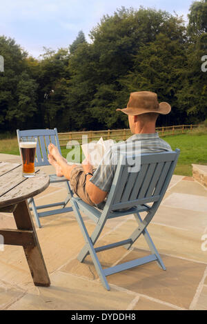 Ein Mann mit einem Buch und Glas Bier entspannen. Stockfoto