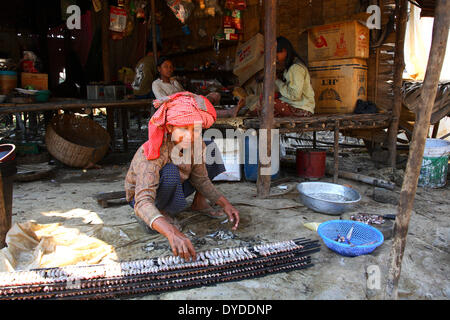 Eine Frau, die Fische auf den Rost vor dem verlassen sie zum Trocknen setzen. Stockfoto