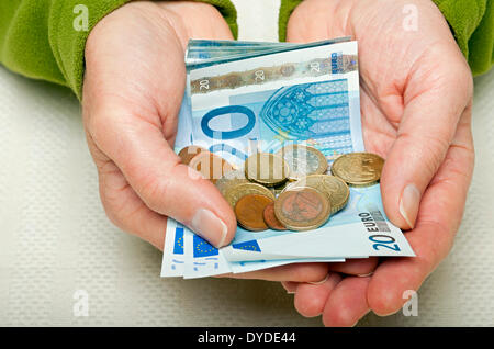 Hände halten 20 Euro-Banknoten und Münzen. Stockfoto