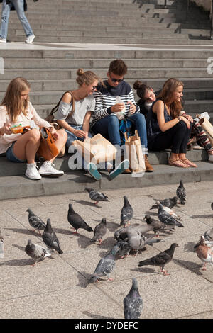 Touristen auf den Stufen der St. Pauls Cathedral in London die Tauben füttern. Stockfoto