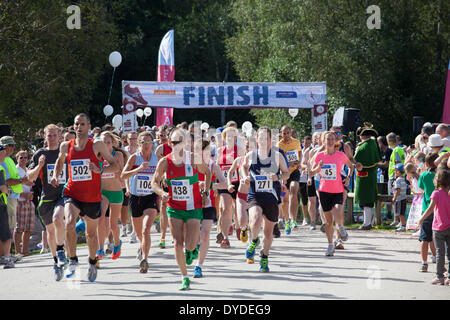 Läufer ab 10k und 5 k laufen bei Alice Holt Wald mit Finish-Zeichen. Stockfoto