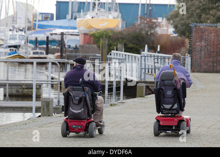 Zwei Männer im motorisierten Rollstuhl auf dem Kai in Lymington. Stockfoto