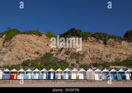 Reihe von hellen Strandhütten unter dem Felsen am Strand von Swanage. Stockfoto