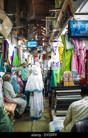 Eine zeitgenössische muslimische Familie in traditioneller Kleidung zu stoppen für eine Diskussion auf einem Tuch-Großmarkt. Stockfoto