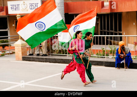 Zwei junge Frauen laufen, winken die indische Flagge auf der Indien und Pakistan Grenze ändern der feierlichen wachen. Stockfoto