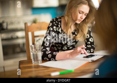 Ein 16 Jahre altes Mädchen Mathe Hausaufgaben auf dem Küchentisch. Stockfoto