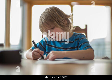 Sieben Jahre alter Junge Zeichnung am Tisch. Stockfoto