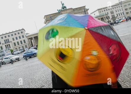 Berlin, Deutschland. 15. April 2014. Eine Frau steht vor dem Brandenburger Tor mit einem Multi-Color-Schirm in Berlin, Deutschland, 15. April 2014. Foto: Paul Zinken/Dpa/Alamy Live News Stockfoto