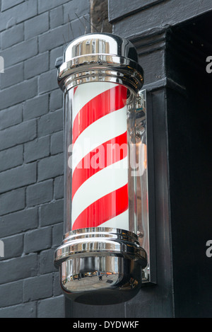 Rote und weiße Barber Shop Pole an eine Wand vor einem Geschäft im Vereinigten Königreich Stockfoto