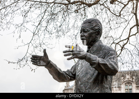 Statue des südafrikanischen Präsidenten Nelson Mandela Holding Narzissen im Frühjahr in Parliament Square, London, UK Stockfoto