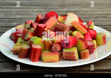 Teller mit Rhabarber Stücke ausschneiden auf einem Gartentisch. Stockfoto