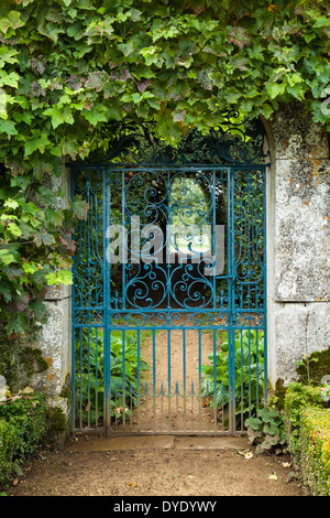 Die reich verzierten schmiedeeisernen Tor der ummauerten Garten Rousham House in einem Cotswold Steinbogen und umrahmt von Weinblättern, Oxfordshire, England Stockfoto