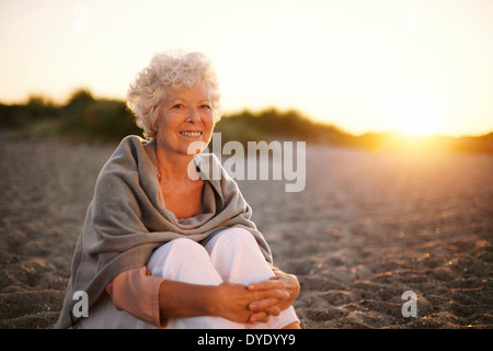 Porträt von lächelnden alte Frau am Strand sitzen. Senior kaukasischen Frauen entspannen im freien Stockfoto