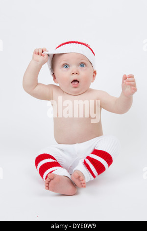 Sechs Monat alten Baby Boy im sportlichen Outfit zerren an seine Mütze Stockfoto