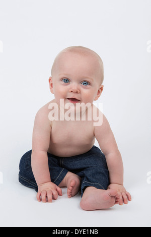 Fröhlicher sechs Monate altes Baby-Junge trägt Blue Jeans Stockfoto