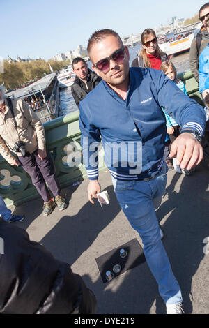 Ein Hütchenspiel Praktiker auch bekannt als Thimblerig, drei Muscheln und eine Erbse Glücksspiel mit Urlaub Menschenmassen auf Westminster Bridge, London Fotografie seiner Tätigkeit zu verhindern versucht. Stockfoto