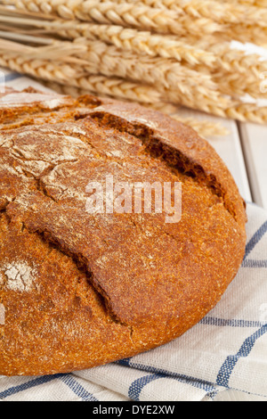 Ganzen Laib frisches Brot mit Ähren auf Tisch Stockfoto