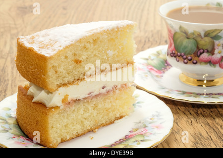 Ein Stück von Victoria Biskuit mit einem heißen Getränk serviert in einem Bone China Tasse und Untertasse Stockfoto