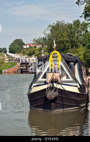 Ein Narrowboat vertäut am unteren Rand der Flug der Verriegelungen auf dem Kennet & Avon Kanal in Caen Hill in der Nähe von Devizes, Wiltshire, UK Stockfoto