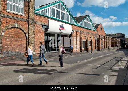 Menschen, die zu Fuß in Richtung der Zeichen & Eingang für das McArthur Glen Designer Outlet Village in Swindon, Wiltshire, UK an einem sonnigen Tag Stockfoto