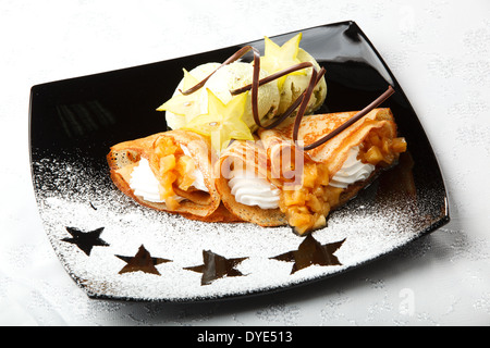 Goldene Pfannkuchen mit Karambolen und Sahne Stockfoto