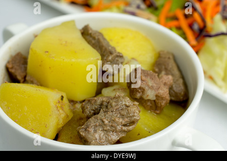 Rindsgulasch mit Kartoffeln in einer Terrine. In der Nähe von Salat aus frischen Gemüsen. Stockfoto