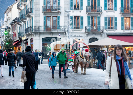 Fußgänger gehen vorbei an einem Pferd gezogenen Buggy in Fell an der Rue du Docteur Paccard im Dorf Chamonix Mont-Blanc abgedeckt. Stockfoto