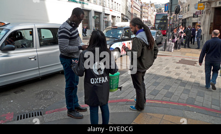 Ein Oxfam Charity Arbeiter auf der Straße arbeiten mit einer Spende, Geld sammeln von Passanten in Central London England UK KATHY DEWITT Stockfoto