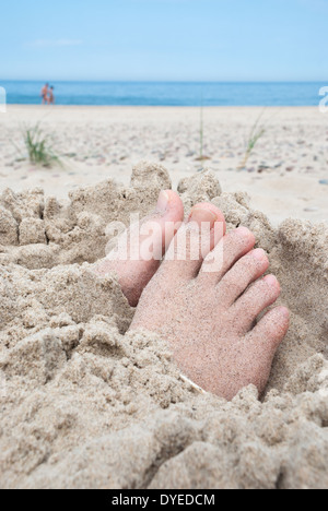 Füße im Sand mit ungedeckten Zehen an einem Strand begraben Stockfoto