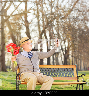 Senior mit Blumen und Selfie im park Stockfoto