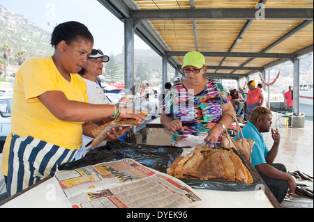 Frau kauft Räucherfisch in Kalk Bay Harbor Markt, Western Cape, Südafrika Stockfoto