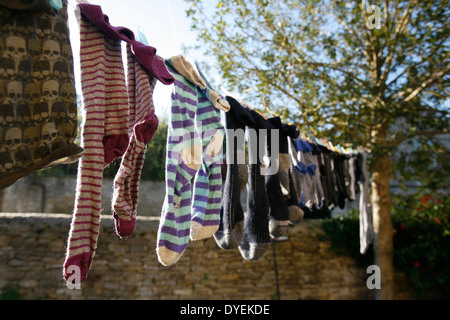 Eine Mischung aus verschiedenen Socken aufhängen und trocknen auf eine Wäscheleine draußen. Stockfoto