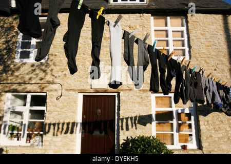 Eine Mischung aus verschiedenen Socken aufhängen und trocknen auf eine Wäscheleine draußen. Stockfoto