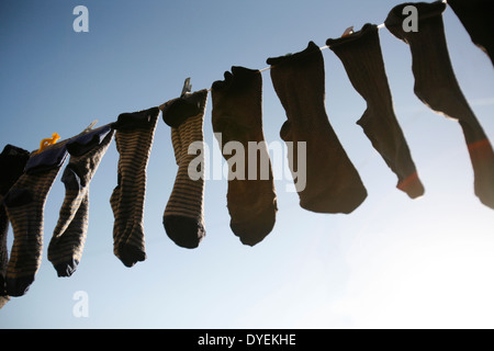 Eine Mischung aus verschiedenen Socken aufhängen und trocknen auf eine Wäscheleine draußen. Stockfoto