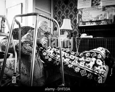 Alte im Alter Dame saß in ihrem Stuhl mit ihrer Katze auf ihrem Schoß und Audio-Handys in ihren Ohren Stockfoto