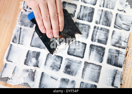 Arbeitnehmer gilt Fugenmasse auf grauen Fliesen Stockfoto