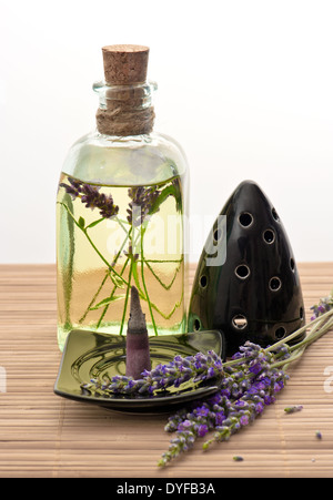 pflanzliches ätherisches Lavendelöl mit Räucherstäbchen und frischen Blumen Stockfoto