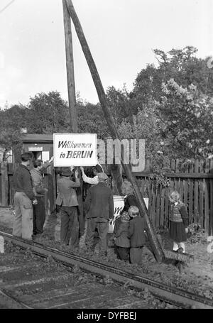 Berliner befestigen Sie ein Schild mit dem Abonnement "Welcome to Berlin" an der Route des Interzonenturnier Zuges im Mai 1949. Nach der Aufhebung der Berlin-Blockade am 12. Mai 1949, wurde der Bahnverkehr zwischen Berlin und den Westzonen wieder in Betrieb genommen. Stockfoto