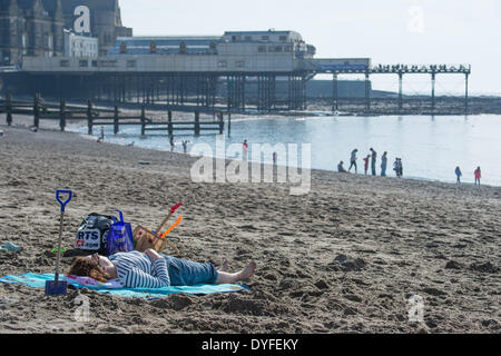 Aberystwyth, Wales, UK. 16. April 2014.   Menschen, die die Sonne am Strand von Aberystwyth zu Beginn des Osterfestes Ferienzeit zu genießen.   Die Temperatur im Westen Wales Resort erreicht die hohe Teens Celsius am späten Nachmittag. Der Wetterbericht wird trüber und nasser in den kommenden Tagen werden aber Erwärmung wieder vom Ostersonntag Bildnachweis: Keith Morris/Alamy Live-Nachrichten Stockfoto