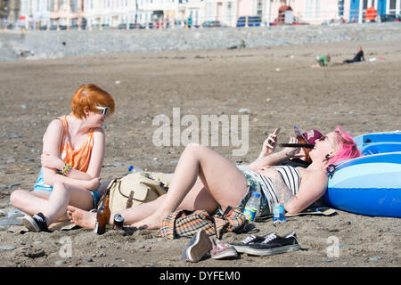 Aberystwyth, Wales, UK. 16. April 2014.   Menschen, die die Sonne am Strand von Aberystwyth zu Beginn des Osterfestes Ferienzeit zu genießen.   Die Temperatur im Westen Wales Resort erreicht die hohe Teens Celsius am späten Nachmittag. Der Wetterbericht wird trüber und nasser in den kommenden Tagen werden aber Erwärmung wieder vom Ostersonntag Bildnachweis: Keith Morris/Alamy Live-Nachrichten Stockfoto