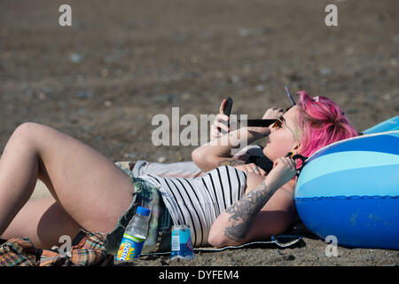 Aberystwyth, Wales, UK. 16. April 2014.   Menschen, die die Sonne am Strand von Aberystwyth zu Beginn des Osterfestes Ferienzeit zu genießen.   Die Temperatur im Westen Wales Resort erreicht die hohe Teens Celsius am späten Nachmittag. Der Wetterbericht wird trüber und nasser in den kommenden Tagen werden aber Erwärmung wieder vom Ostersonntag Bildnachweis: Keith Morris/Alamy Live-Nachrichten Stockfoto