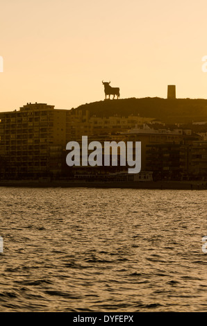 Sonnenuntergang an der Küste von Fuengirola mit Osborne Stier, der einem spanischen Wahrzeichen geworden ist. Costa Del Sol, Spanien. Stockfoto