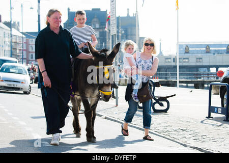 Aberystwyth, Wales, UK. 16. April 2014.   Menschen genießen einen Esel reiten in der Sonne auf der Promenade in Aberystwyth zu Beginn des Osterfestes Ferienzeit.   Die Temperatur im Westen Wales Resort erreicht die hohe Teens Celsius am späten Nachmittag. Der Wetterbericht wird trüber und nasser in den kommenden Tagen werden aber Erwärmung wieder vom Ostersonntag Bildnachweis: Keith Morris/Alamy Live-Nachrichten Stockfoto