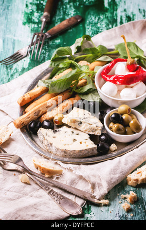 Gemischte Antipasti Blauschimmelkäse, Oliven und Mozarella auf silbernen Tablett über grüne Holztisch mit serviert Vintage Gabeln. Stockfoto