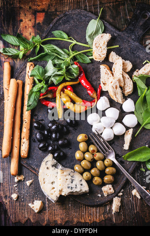 Gemischte Antipasti Brot-sticks, Oliven und Mozzarella auf gusseisernen Board über Holztisch mit Vintage Gabel serviert. Ansicht von oben. Stockfoto